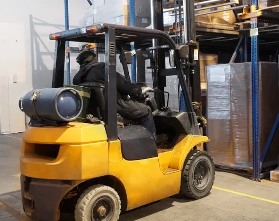 Wózek widłowy gazowy podczas umieszczania palety w gnieździe magazynowym - get-a-truck.pl
