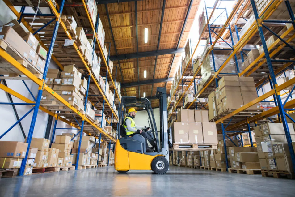 Wózek widłowy podczas transportu towarów w magazynie - get-a-truck.pl
